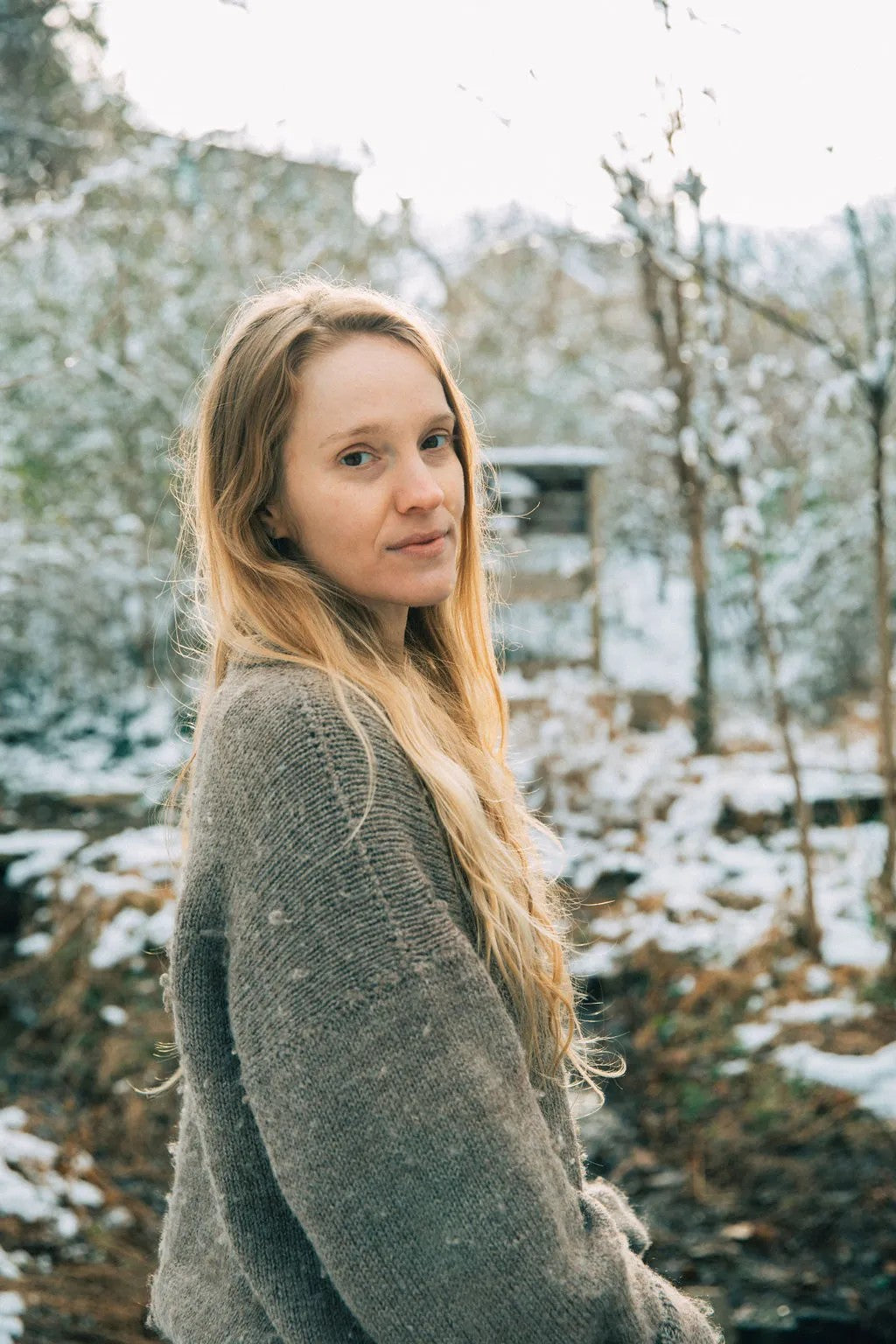 Hannah Delynn in a grey sweater in a snowy winter landscape